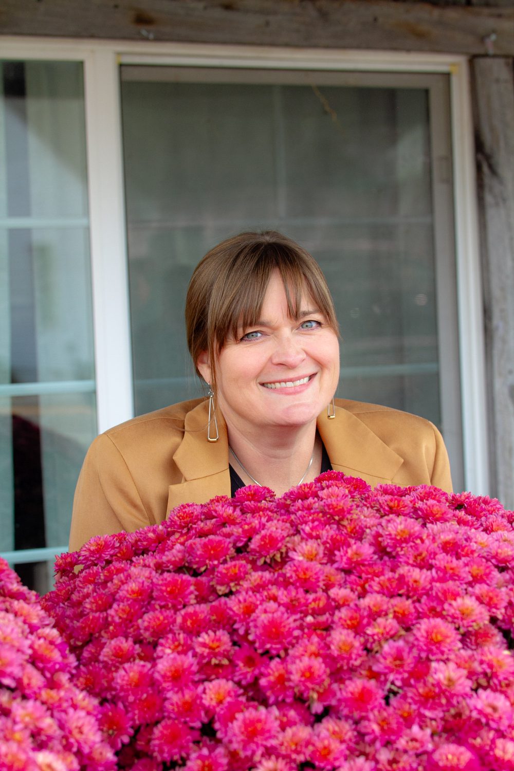 Regina Taute smiling behind a bouquet of pink flowers